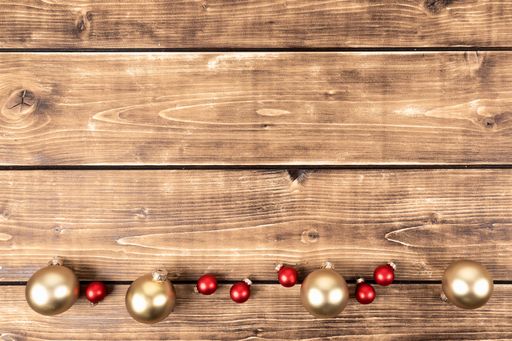 A closeup shot of red and gold Christmas balls on the wooden background