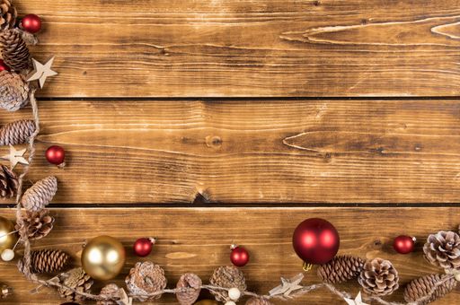 A top view of a Christmas wooden frame with red and gold balls and pine cones