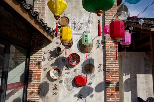 A wall with bowls hanging from it in China and Chinese lamps in the background