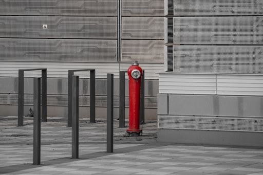 A red fire hydrant near a gray building