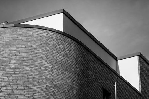 A low angle grayscale shot of the top part of exterior design of a building