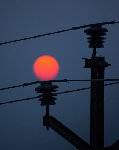 A vertical shot of sunset on top of an electric wire pole