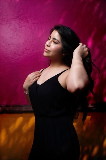 An attractive Hispanic woman flipping her hair against a colorful wall in Mexico