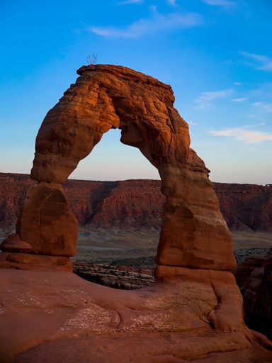 A vertical shot of a delicate sandstone arch in Arches National Park in Utah