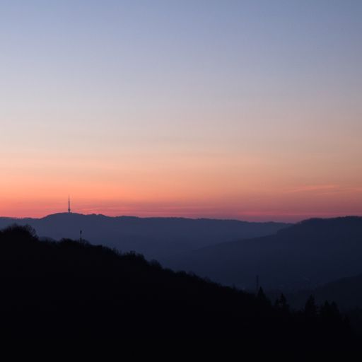 The dark silhouettes of the hills against the sky at sunset. Czech Republic, Bukova hora TV Tower in the background.