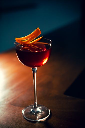 A vertical shot of a refreshing cocktail on a wooden table in dim lighting.