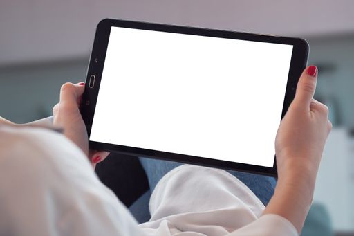 A woman holding an iPad in her hands in the living room.