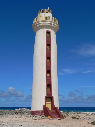 A vertical shot of a white lighthouse on a beach in Bonaire Island