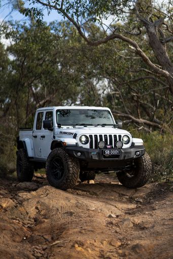 A white Rubicon jeep parked on a dirt trail in a park