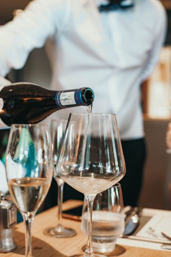 A vertical shot of a server pouring wine into a glass at a restaurant in Cape Town, South Africa