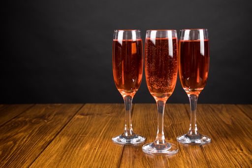 A glasses with champagne on a wooden table near gray wall