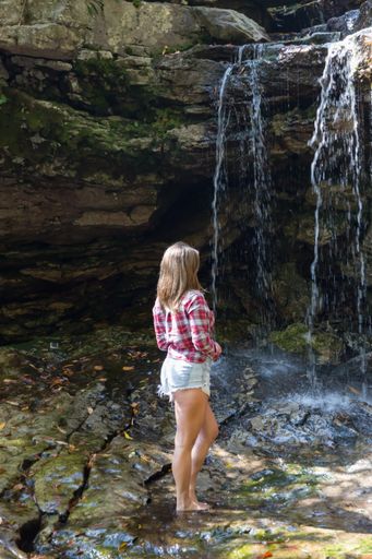 Beautiful young woman in red flannel shirt looks at Big Run Falls on Big Run Creek in Tucker County West Virginia