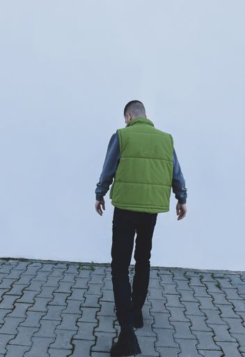 attractiveyoung man model in green gilet and black boots posing next to white wall