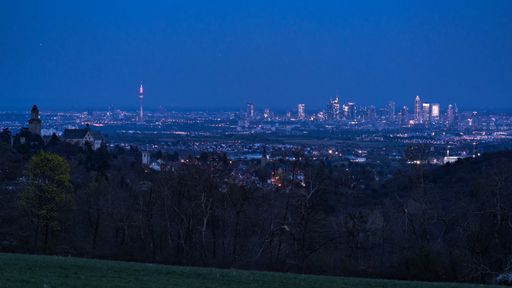 A distant night view of the cityscape with illuminated buildings in Frankfurt, Germany