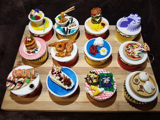 A closeup shot of artistic cupcakes with miniature food toppers on  a wooden board
