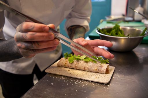 A closeup of a professional chef cooking a wrap in the kitchen of a restaurant