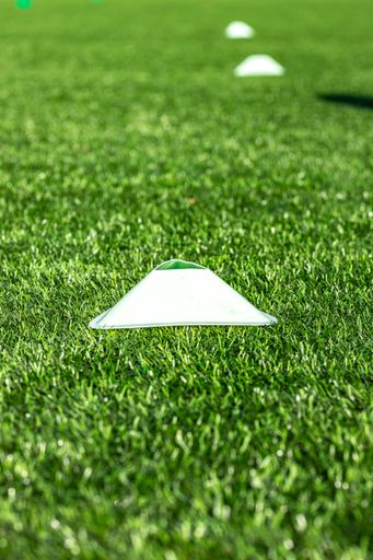 a selective focus shot of a white cone in the football fiel