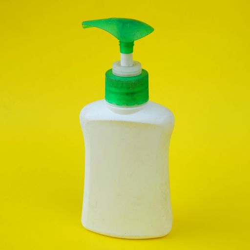 An angle shot of a hand soap dispenser on a yellow background.