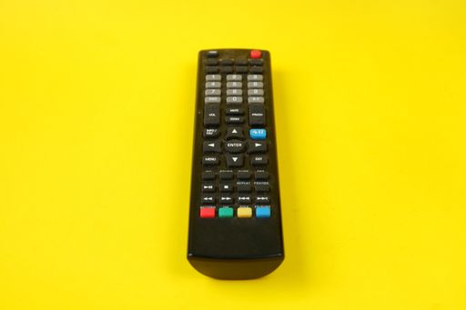 A top shot of a remote control on a yellow background.