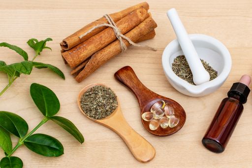 A top view of fresh herbs from the garden and the different types of oils for massage and aromatherapy on wooden table