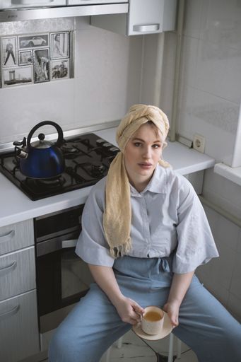 An attractive blonde female model in the kitchen  enjoying a cup of tea