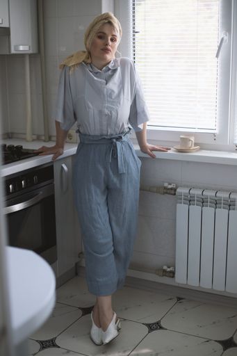 An attractive blonde female model in the kitchen  enjoying a cup of tea
