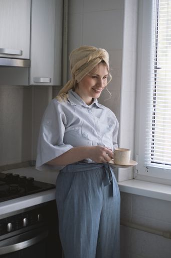 An attractive blonde female model in the kitchen  enjoying a cup of tea
