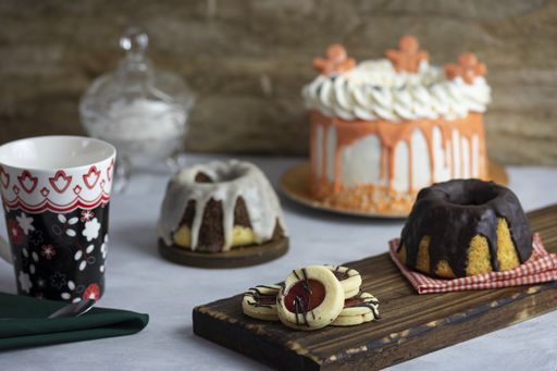 A closeup shot of a sweet table with cake, pudding, plastic cup and strawberry cookies