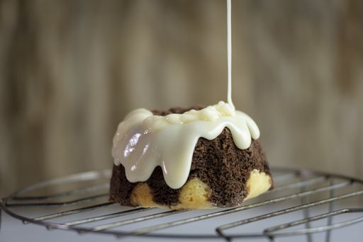 A closeup shot of a cake on a cooling rack poured with white chocolate