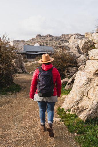 A back shot of an adult Caucasian woman wearing a backpack and waking in El Torcal de Antequera on a sunny day, Malaga, Spain