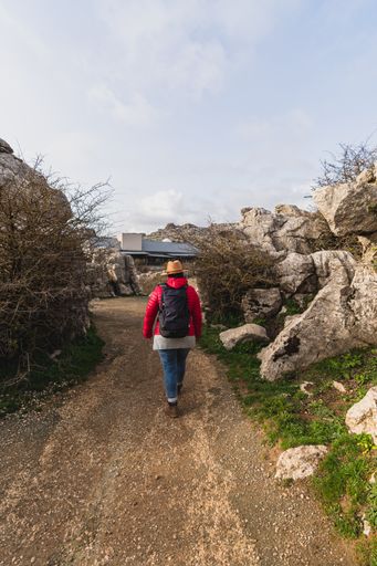 A back shot of an adult Caucasian woman wearing a backpack and waking in El Torcal de Antequera on a sunny day, Malaga, Spain