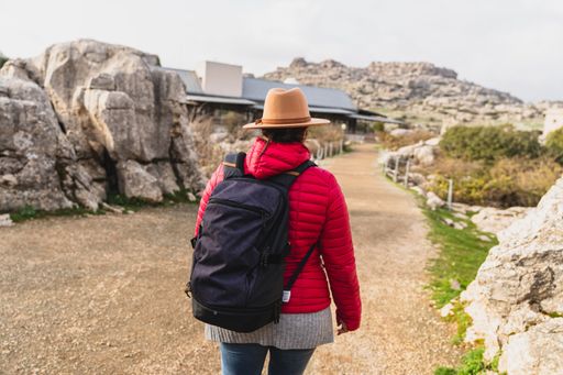 A back shot of an adult Caucasian woman wearing a backpack and standing in El Torcal de Antequera on a sunny day, Malaga, Spain