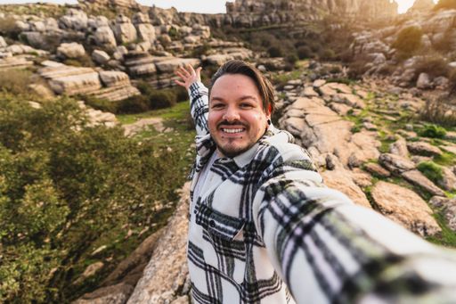 A beautiful shot of a Caucasian man smiling while taking a selfie with her camera in El Torcal de Antequera, Malaga, Spain
