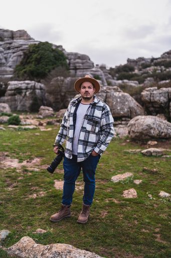 A beautiful shot of an adult Caucasian man holding his camera while standing in El Torcal de Antequera, Malaga, Spain