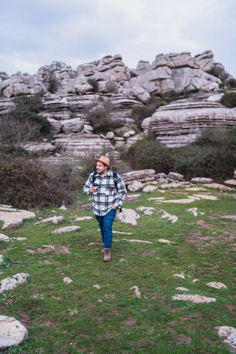 A beautiful shot of an adult Caucasian man holding his coffee while walking in El Torcal de Antequera during daytime, Malaga, Spain