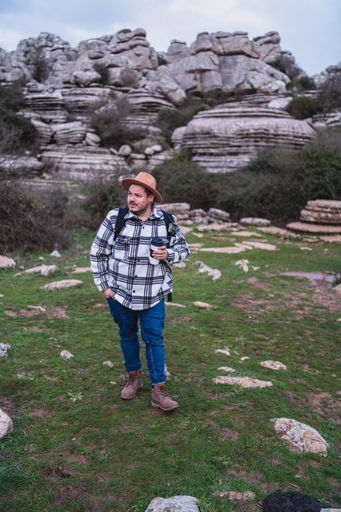 A beautiful shot of an adult Caucasian man holding his coffee while walking in El Torcal de Antequera during daytime, Malaga, Spain