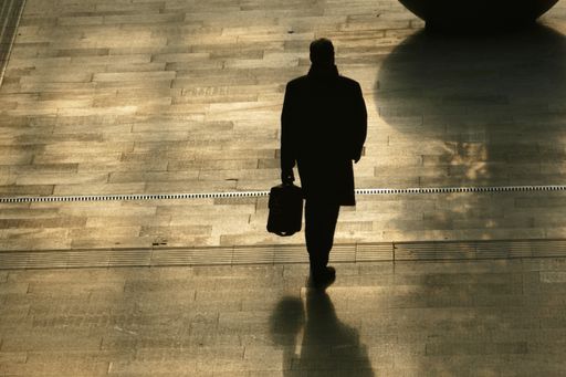 A silhouette of a businessman with a briefcase walking on a road