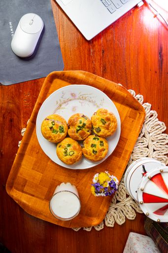 A top view of bacon muffins and white yogurt served on a wooden tray on the working table