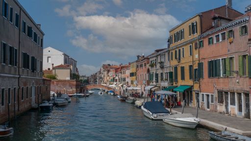 A river with boats and buildings on a sunny day in Venice, Italy