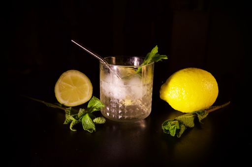 A closeup shot of Lemon mint gin tonic cocktail with lemon and half isolated on a black background