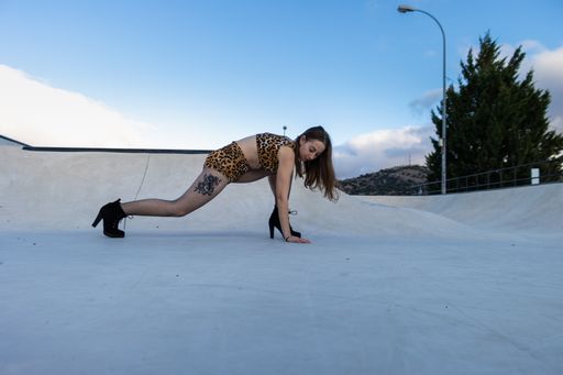 A Caucasian female stretching after dancing on dancing floor outdoors with blue sky