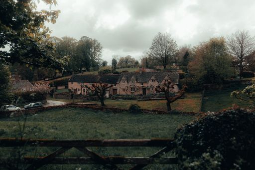 A high angle view of an abandoned house with brick walls and a overgrown garden under the cloudy sky
