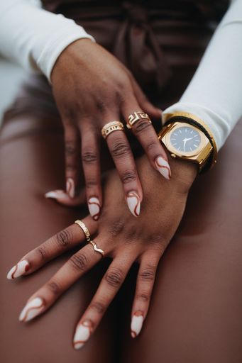 A vertical shot of a person's hands wearing rings and watch for accessories