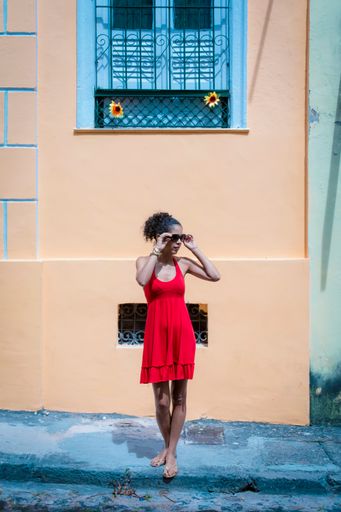 A black woman wearing a red dress and sunglasses on a sunny day in Salvador, Bahia, Brazil