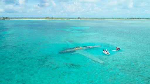 An aerial view of people  in a white tiny boat at Exumas, Bahamas