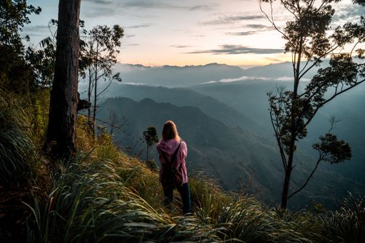 A young female hiker watching the sunrise over Ella Rock in Sri Lanka