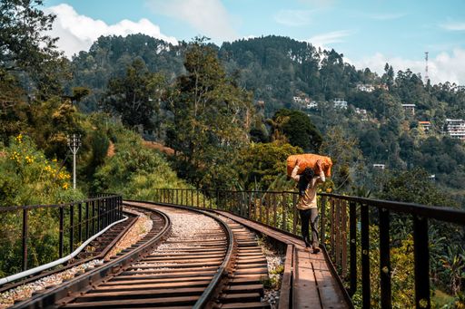 A male worker carrying fabric on his back on train tracks in Sri Lanka