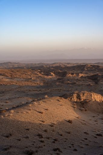 A vertical shot of a desert full of yardangs in daylight under the clear sky