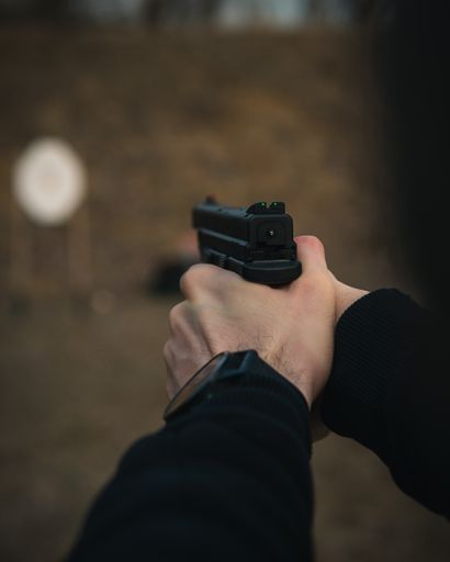 A vertical shot of male hands holding a handgun for shooting