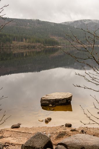 A vertical shot of the Schluchsee Lake with hills, trees and rocks in the Black Forest on a cloudy day